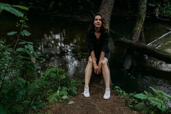 Donna vestita di nero. Cammina in una foresta di conifere scure. Tracciamento e viaggio — Foto Stock