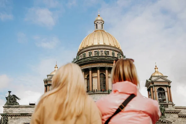 サンクトペテルブルクの聖イサク大聖堂 ぼやけた前景 2人の観光客の女の子 大聖堂に集中しろ 遠足のコンセプト — ストック写真
