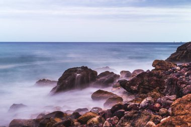 Mazatlan 'da dalgaların taşların üzerinde kırıldığı sahilde uzun süre açık deniz.