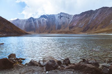 Dağlarla ve mavi gökyüzüyle çevrili kristal bir su gölü..
