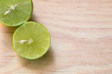 Yeşil sulu bir limon doğal ışıkta yanan tahta bir tahtanın üzerinde kesilir.