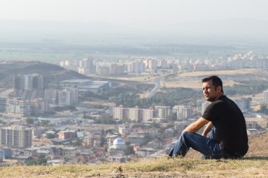 güçlü adam dağın tepesinde şehri seyir siyah giysili
