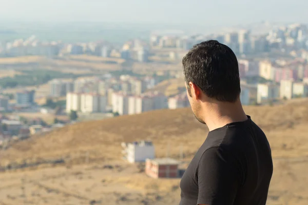 güçlü adam dağın tepesinde şehri seyir siyah giysili