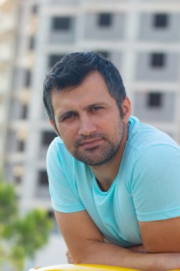 Bina arka plan üzerinde turkuaz bir T-shirt adam esmer