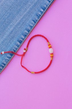 Konu bileklik kırmızı ve mavi jeans pembe bir arka plan üzerinde. moda kot Üstten Görünüm