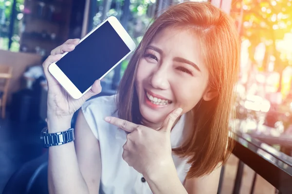 Szépség ázsiai lány mosolyogva, és bemutatja a smartphone — Stock Fotó