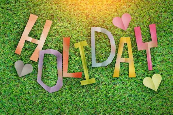 Holiday concept with text paper cut stick on green grass — Stock Photo, Image