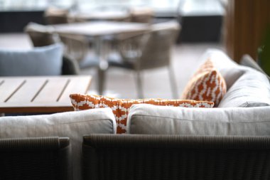 Renkli yumuşak yastıkları kapat. Doğa materyali yemek sandalyesini bulanık veranda alanı iç tasarım konseptiyle düzenle.