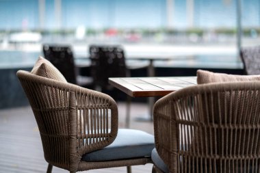 Kafe avlusunda yemek masasını bitiren rattan hasır malzeme. Arka planda bulanık bahçe arka plan iç tasarım konsepti.