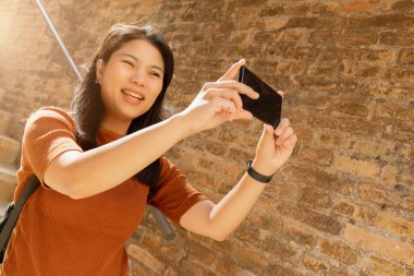 Yeni normal seyahat yaşam tarzı maske takan Asyalı kadın elinde akıllı telefon kamerası ya da kahve fincanı ile eski İtalya 'yı geziyor.