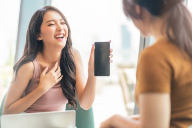 Çekici Asyalı pozitif kadın mutluluğu sohbeti gülümsüyor kafeteryada arkadaşla şakalaşıyor ve sıradan bir hayat tarzının doğal ışığıyla sohbet ediyor.