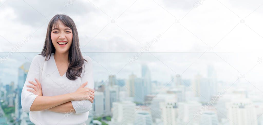 Asian girl wearing white dress toothly smile wide mouth open excited and cheerful with checking result  from smartphone screen display capital building cityscape background