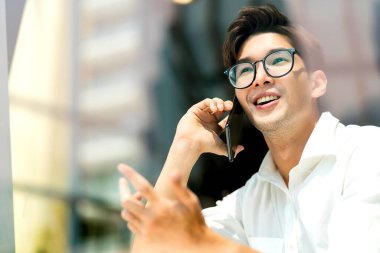 Zeki, çekici, pozitif Asyalı, gözlüklü iş adamı. Uzak mesafeden yeni normal yaşam tarzı el işi. Canlı yayında akıllı telefon konferansı.