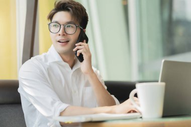 Zeki, çekici, pozitif Asyalı iş adamı gözlüklü, uzaktan kumandalı, yeni normal yaşam tarzı el bilgisayarı kullanan uzaktan kumandalı televizyon konferansında uzaktan kumandalı iş fikirleriyle buluşuyor.