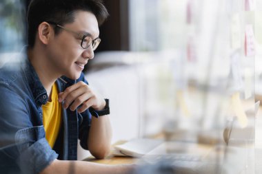 Zeki, çekici, pozitif Asyalı iş adamı gözlüklü, uzaktan kumandalı, yeni normal yaşam tarzı el bilgisayarı kullanan uzaktan kumandalı televizyon konferansında uzaktan kumandalı iş fikirleriyle buluşuyor.