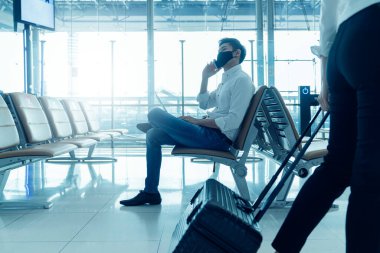 Sosyal uzaklık, yüz maskesi takan işadamı salgın sırasında kovid19 enfeksiyonunu önlemek için dizüstü bilgisayarla oturup birbirlerinden uzak durmaya çalışıyor. Boş sandalye koltuğu kırmızı haç yeni bir normal gösteriyor