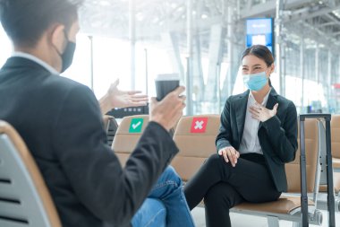 İş adamı ve yüzü maskeli kadın havaalanı terminalinde sosyal uzaklık koltuğu ile günlük görüşme yeni yaşam tarzı iş konsepti