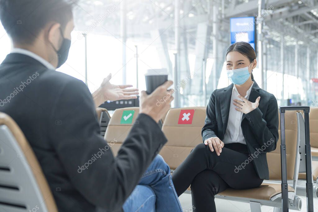 businessman and woman with face mask protection casual meeting with social distancing seat at airport terminal new lifestyle business concept