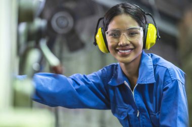 Asyalı kadın profesyonel mühendis üniforması ve güvenlik gözlüğü takıyor. Kalite kontrol, bakım, fabrikada kontrol, fabrikada depo atölyesinde fabrika işletmecileri için kontrol.