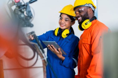 Mühendis erkek ve kadın teknisyen bakım kontrolü robot kol sistemini tablet dizüstü bilgisayarla kaynak yaparak işletim sürecinin kalitesini kontrol altına alıyor ağır endüstri 4.0 üretim fabrikası