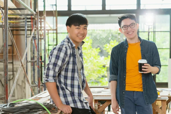 smiling asian teamwork of yound interior dreative designer portrait stand together hand chest confident and smart team with background of construction home renovate