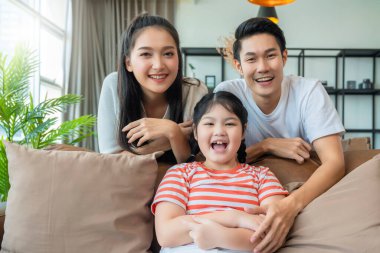 Mutlu Neşe portresi Çekici Genç Asyalı Aile Portresi Aile Günü konsepti Asyalı aile erkeği kadın ve küçük kız kanepede birlikte iyi vakit geçiriyorlar