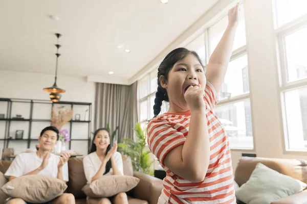 在客厅里 亚洲可爱的家庭在电视机前欣赏着小女孩的歌舞表演 开心极了 — 图库照片