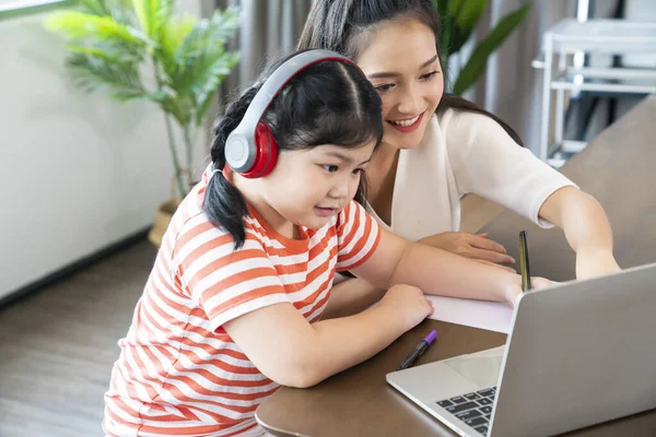 asian mother enjoy teach and explain homework to child daughter for online study during homeschooling at home ,home quarantine, online learning education new normal lifestyle