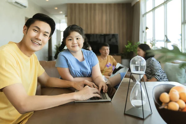 年轻的亚洲父亲在家里用笔记本电脑和大家庭的妈妈 外祖母一起工作 开心的笑着坐在沙发上 坐在客厅里 — 图库照片