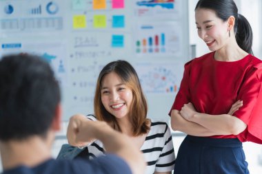 Zeki Asyalı girişimci, kendine güvenen küçük girişimci, arkadaşlarının portresi beyaz pano ve işletme finans tablosu ile ortaklaşa toplantı beyin fırtınası yapıyor. Ofis arka planında da kağıt çizelgesi var.