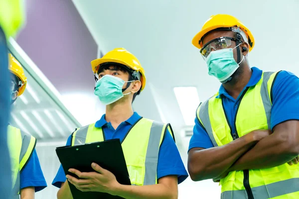 Professional engineering walking discuss inspecting with engineer team in clean room machinery factory area. Manager hand use tablet listenreport paper for internal audit. Quality assurance for manufacturing. New normal factory concept