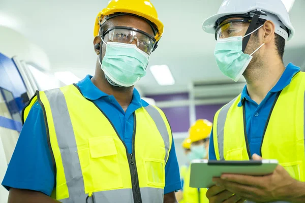 Professional engineering wearing mask discuss with engineer team in clean room machinery factory area. Manager hand use tablet listen report paper for internal audit. Quality control process