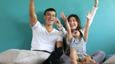 Güzel bir an aile kavramı. Kız ve ebeveynin yumuşak yatak saatinde battaniyede birlikte oynamaları.