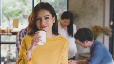 Güzel Asyalı kadın, iş ortağıyla birlikte sıcak kahve içiyor. Kamera arkasında büyüleyici ve özenli bir kafe restoranı geçmişi var.