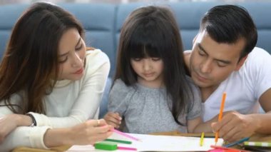 Şirin siyah saçlı kız çocuk, ev ödevi ve ebeveyni ile birlikte oturma odası konseptine gülmek.
