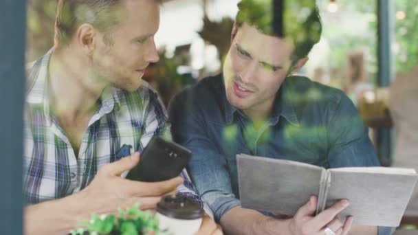 Zwei Geschäftspartner beraten Geschäftsstrategie mit Glück Hand halten Smartphone im Café Hintergrund in der Nähe von Fenster — Stockvideo
