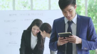 Asyalı akıllı iş adamı elinde akıllı telefon ya da tablet aygıt iletişimi Asyalı kadın takım desteği beyin fırtınası iş görüşmeleri konseptinin arkasındaki tartışmadır.