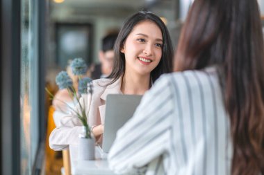 Asyalı kadın kreatif ajans gündelik toplantı tartışması ev müşterisi iş arkadaşı ile laptop kahve işi pencere ve su damlası yağmuru arka planda Asyalı genç kadın