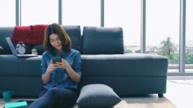 Çevrimiçi alışveriş fikirleri konsepti. Güzel Asyalı kadın mutlu ve neşeli bir şekilde akıllı telefon dükkanından ürün seçip seçmeyi seviyor.