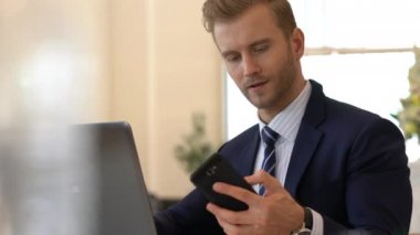 Takım elbiseli yakışıklı beyaz iş adamı laptopla iletişim ve akıllı telefon ofisi geçmişi.