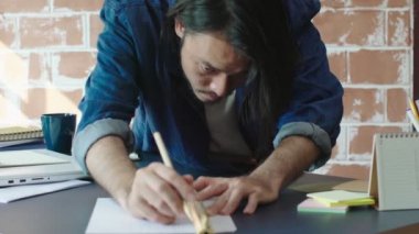Zeki Asyalı erkek mimar mimari modeli ile çalışıyor. Malzeme seçiyor ve toplu model ev tasarımı kavramını inceliyor.
