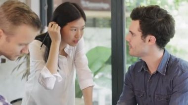 Modern tasarım ofisinde dizüstü bilgisayar ve kağıt dökümanlarıyla konuşan yaratıcı tasarımcı grubu