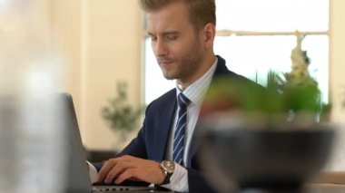 Takım elbiseli yakışıklı beyaz iş adamı laptopla iletişim ve akıllı telefon ofisi geçmişi.