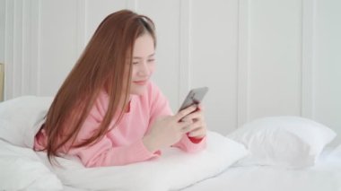 Güzel, uzun saçlı Asyalı kadın. Güzel gülümseme. Akıllı telefon sohbetinin tadını çıkar.