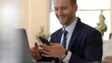 Takım elbiseli yakışıklı beyaz iş adamı laptopla iletişim ve akıllı telefon ofisi geçmişi.