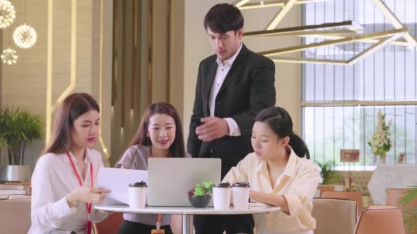 Grupa biznesmenów i kobiet rozmawiających na spotkaniu w nowoczesnym biurze projektowym z laptopem i dokumentem papierowym — Wideo stockowe
