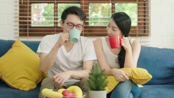 Счастье азиатская пара семейный брак наслаждаться утренние разговоры вместе с любовью и отношения на диване с ноутбуком и кофе домашний фон интерьера — стоковое видео