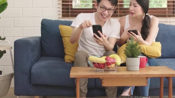 Pasangan bahagia manis menikmati permainan di smartphone bersama-sama ruang tamu latar belakang rumah — Stok Video