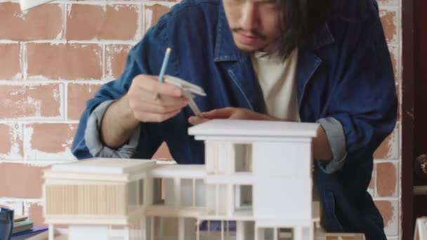 Intelligens ázsiai férfi Építész dolgozik az ő építészeti modell kiválasztása anyag és tanulmány tömeg modell ház tervezési ötletek koncepció — Stock videók