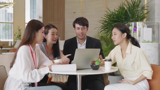 Grupa biznesmenów i kobiet rozmawiających na spotkaniu w nowoczesnym biurze projektowym z laptopem i dokumentem papierowym — Wideo stockowe
